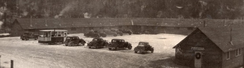 Black and white image of the Officer's Quarter at Camp Charles Smith in Waterbury.  It is a single-story u-shaped building with cars parked in the center and along the open edge.